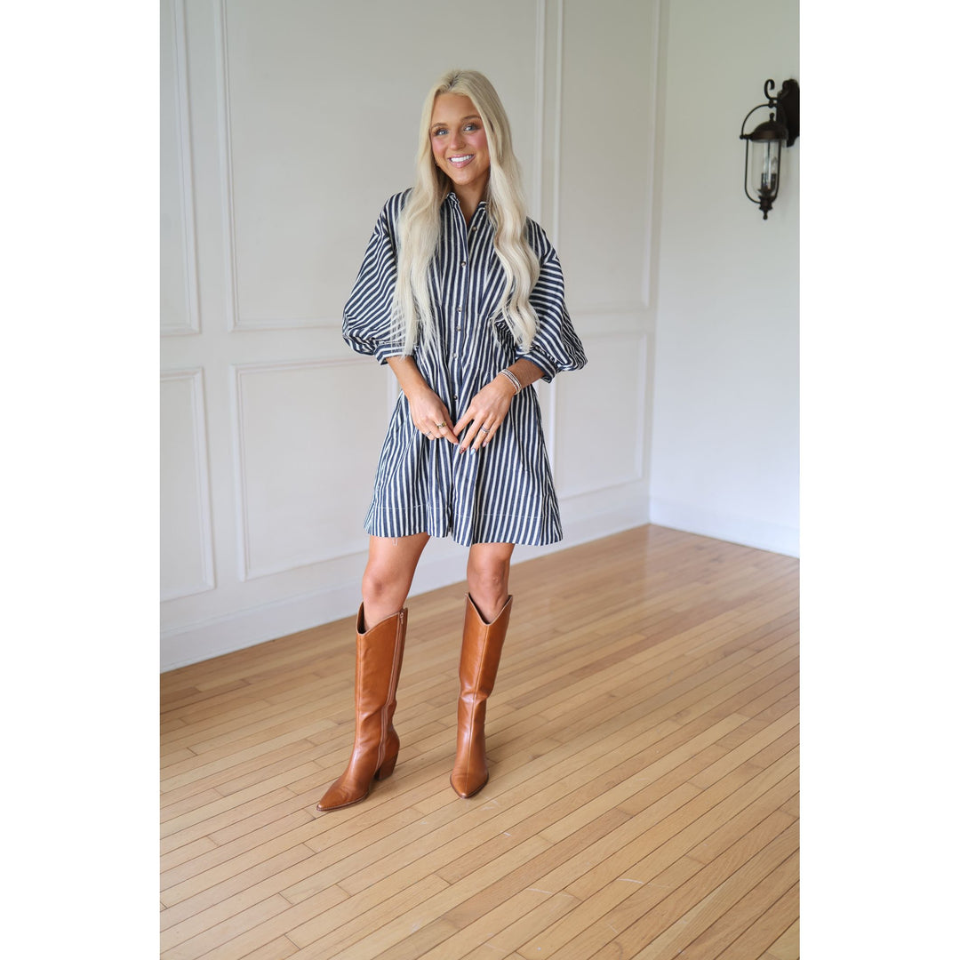 Woman wearing a striped dress and brown knee-high boots 