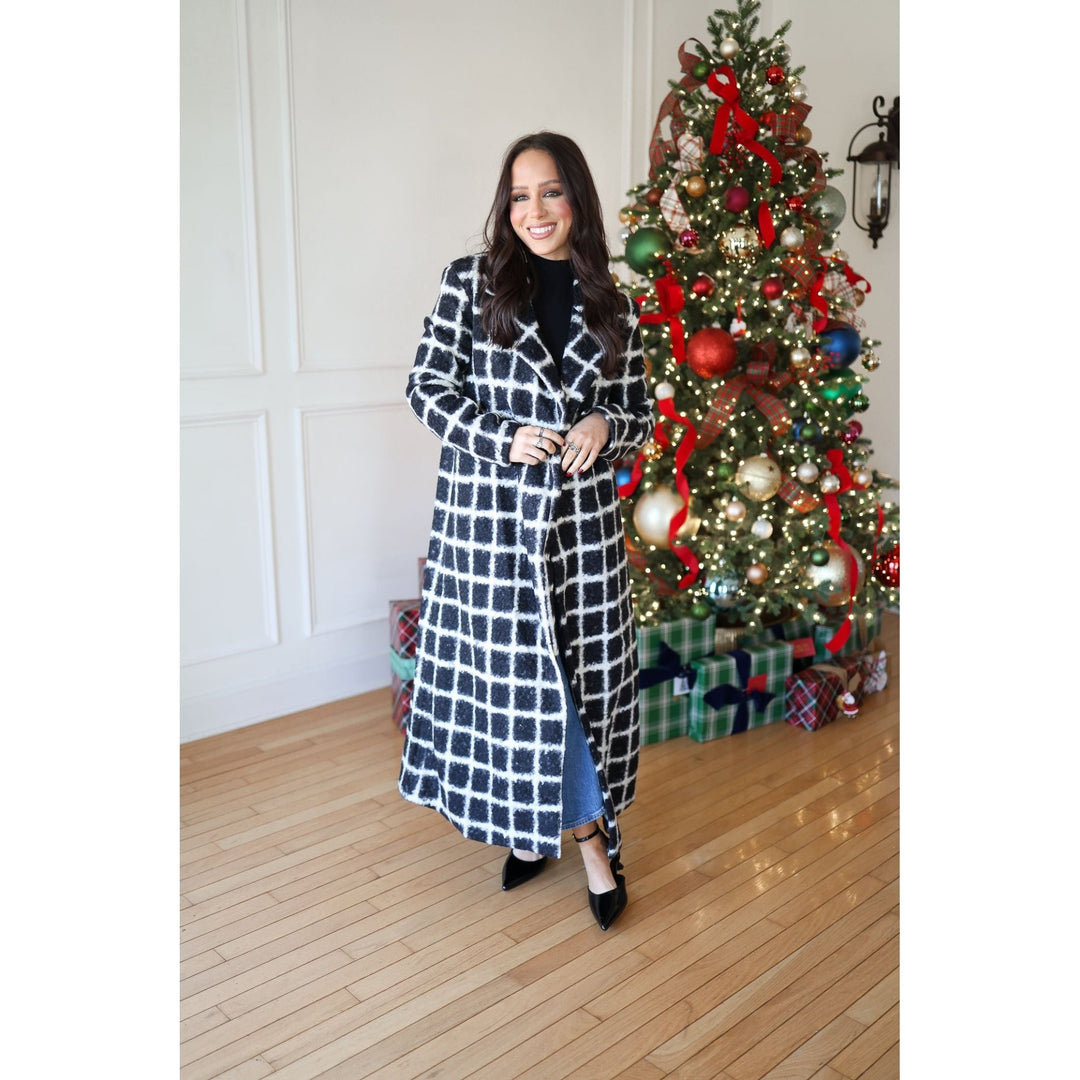 Woman in a checkered dress standing in front of a decorated Christmas tree.