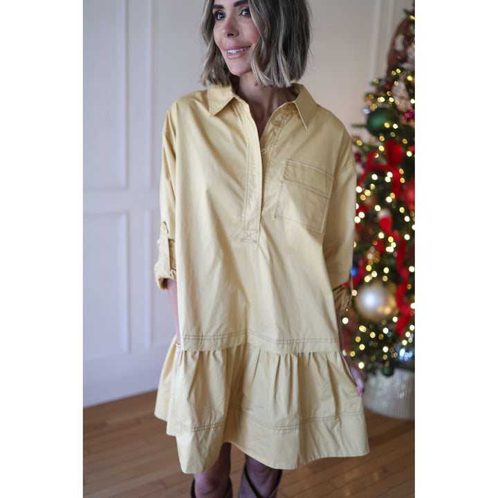 Woman wearing a yellow dress standing in front of a decorated Christmas tree.
