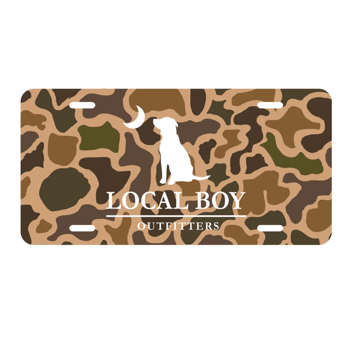 Camouflage-patterned license plate with a dog silhouette and 'Local Boy Outfitters' text on a white background.