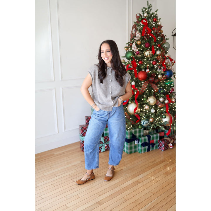 Woman standing next to a decorated Christmas tree with presents underneath.