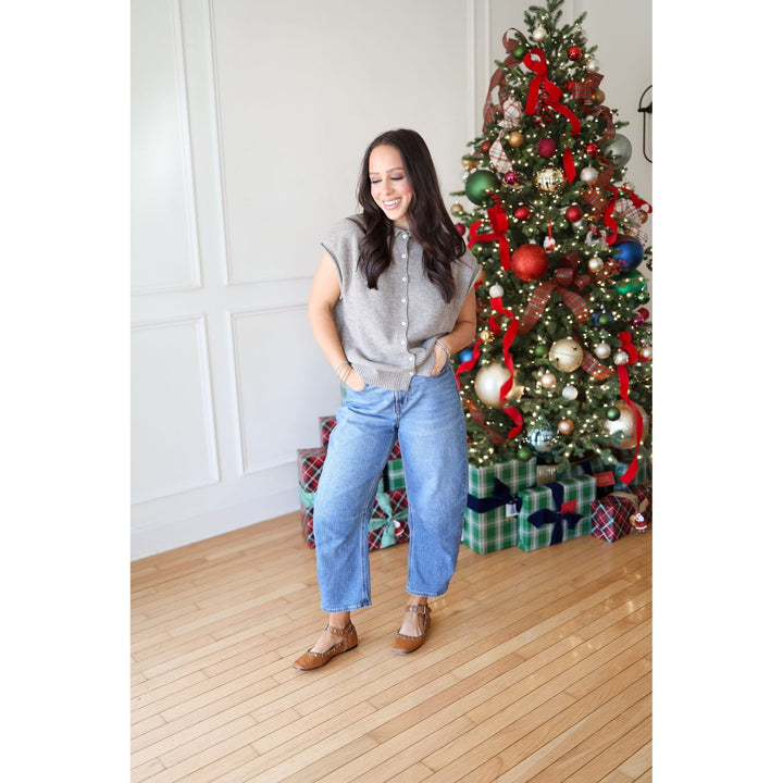 Woman standing in front of a decorated Christmas tree with presents underneath.