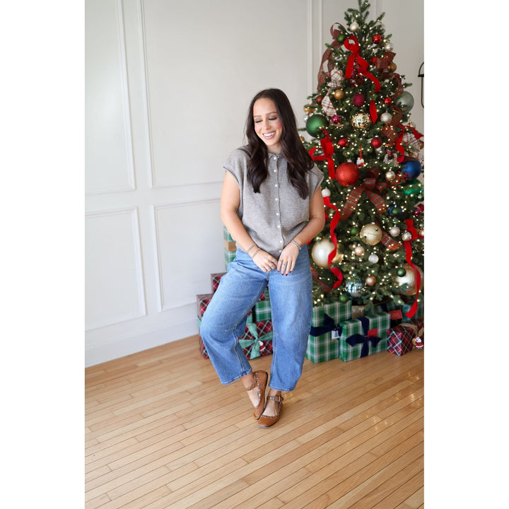 Woman standing in front of a decorated Christmas tree with presents underneath.