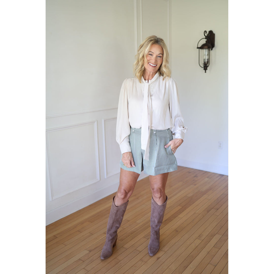 Woman wearing a white blouse, skirt, and knee-high boots 
