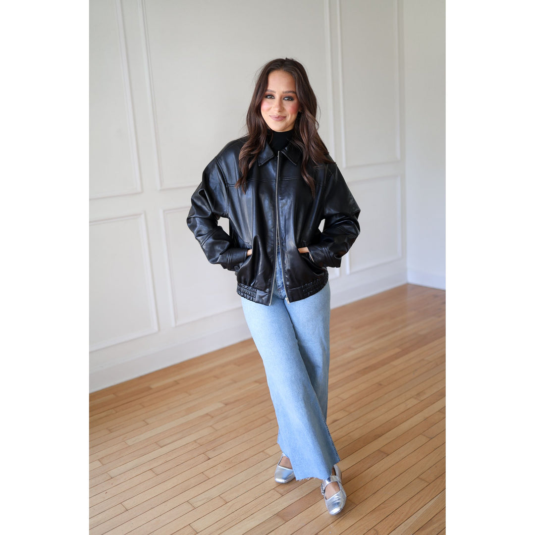 Woman wearing a black leather jacket and light blue jeans 