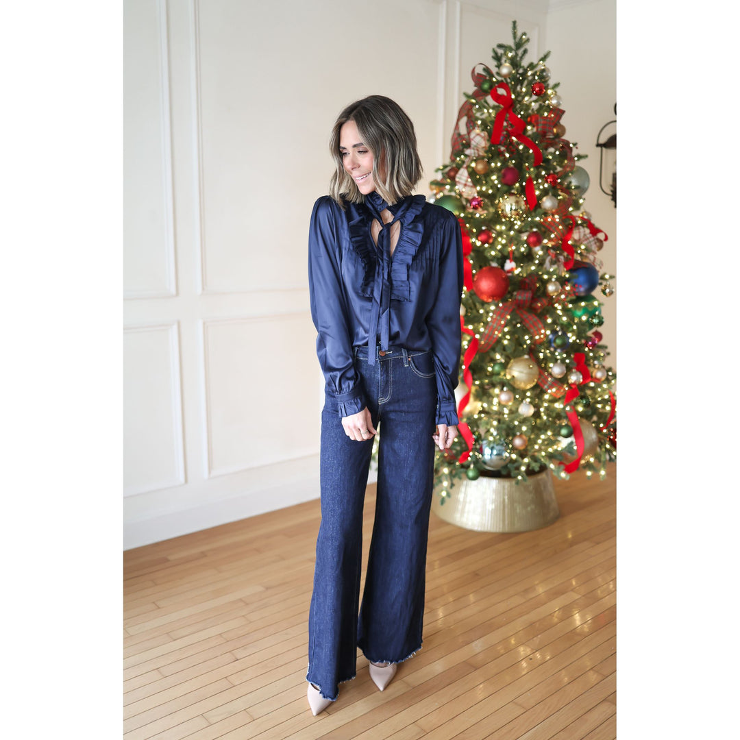 Woman in a blue outfit standing in front of a decorated Christmas tree.