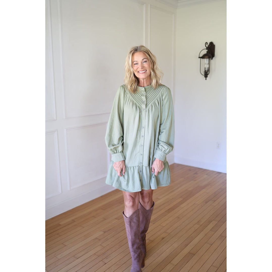 Woman wearing a light green dress and brown knee-high boots
