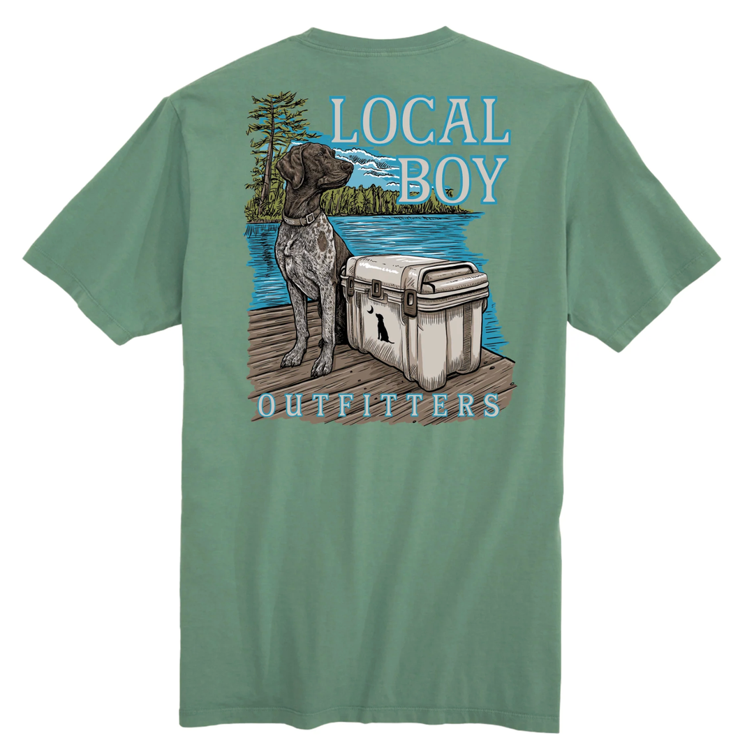 Green t-shirt with a graphic of a dog by a cooler and 'Local Boy Outfitters' text on a white background