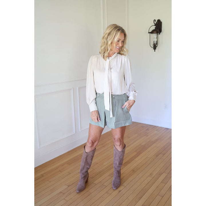 Woman wearing a white blouse, plaid skirt, and brown knee-high boots 