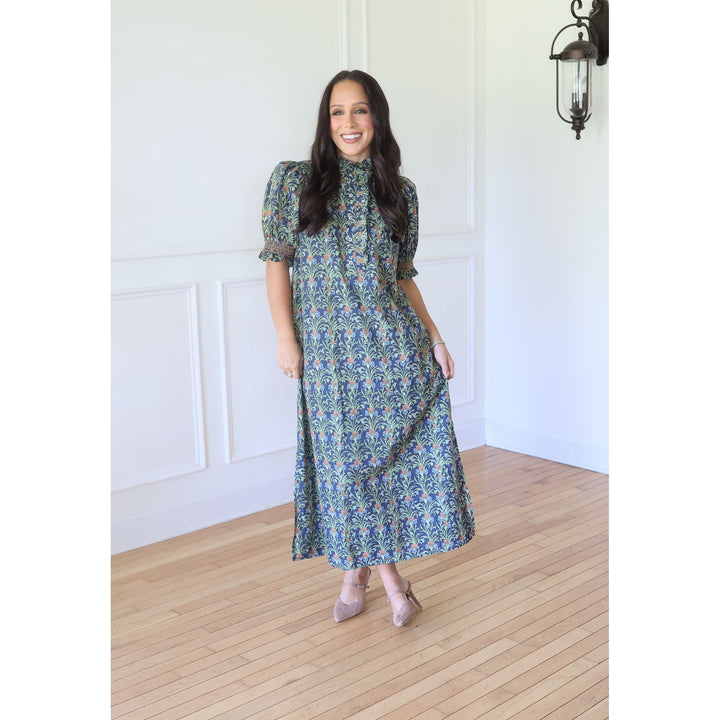 A woman modeling a long-sleeve midi dress with a blue and green floral pattern