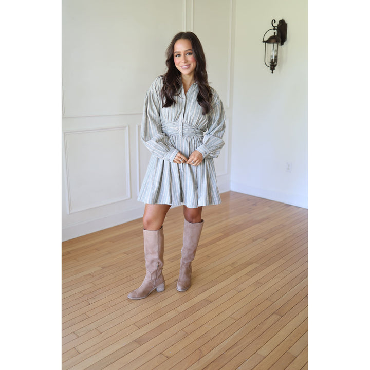 Woman in a light-colored dress and beige knee-high boots 