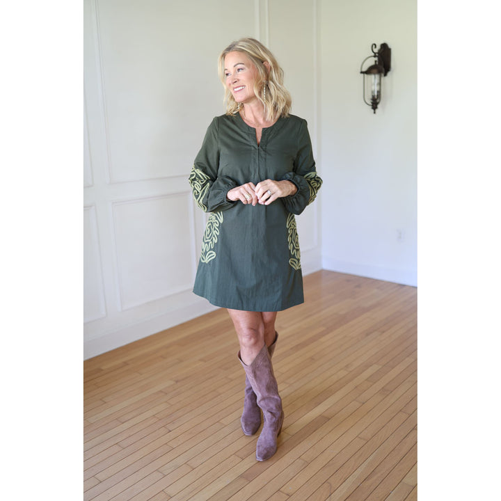 Woman wearing a green dress with decorative sleeves and hem 