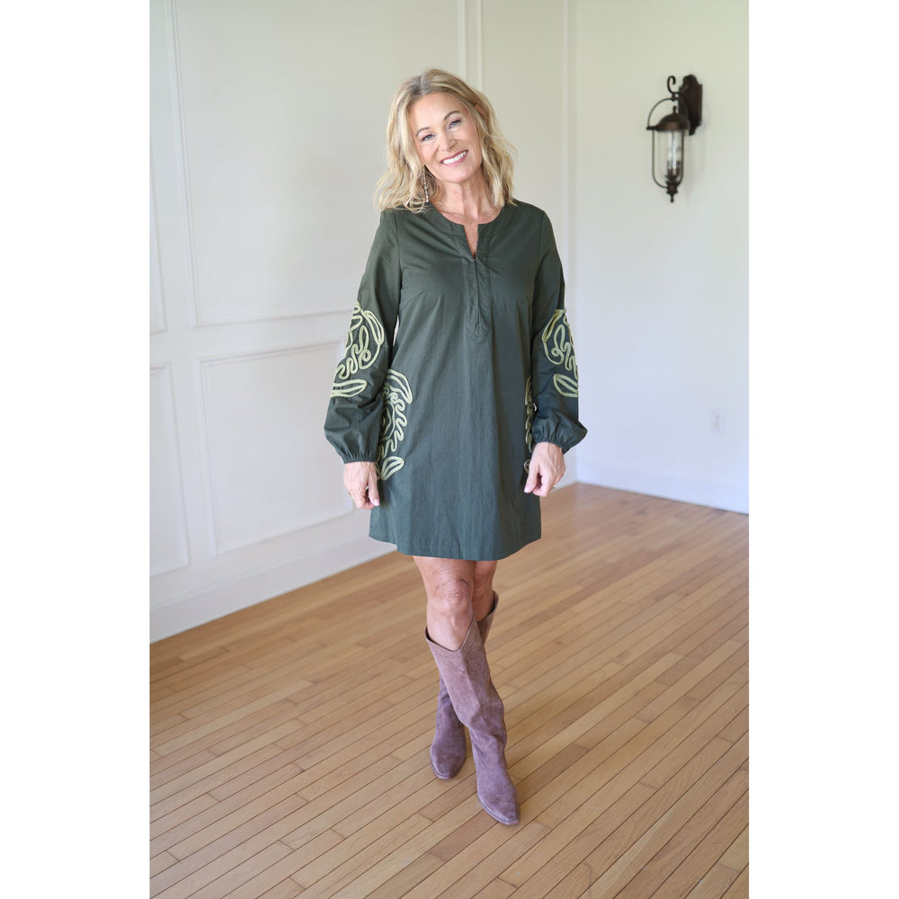 Woman wearing a green dress with long sleeves and patterns