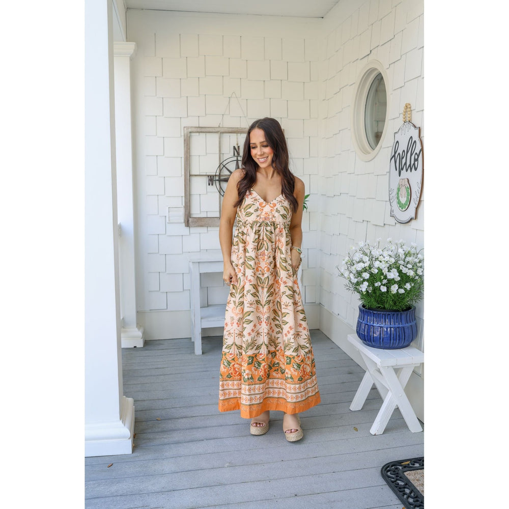 Woman in a floral dress standing on a porch 