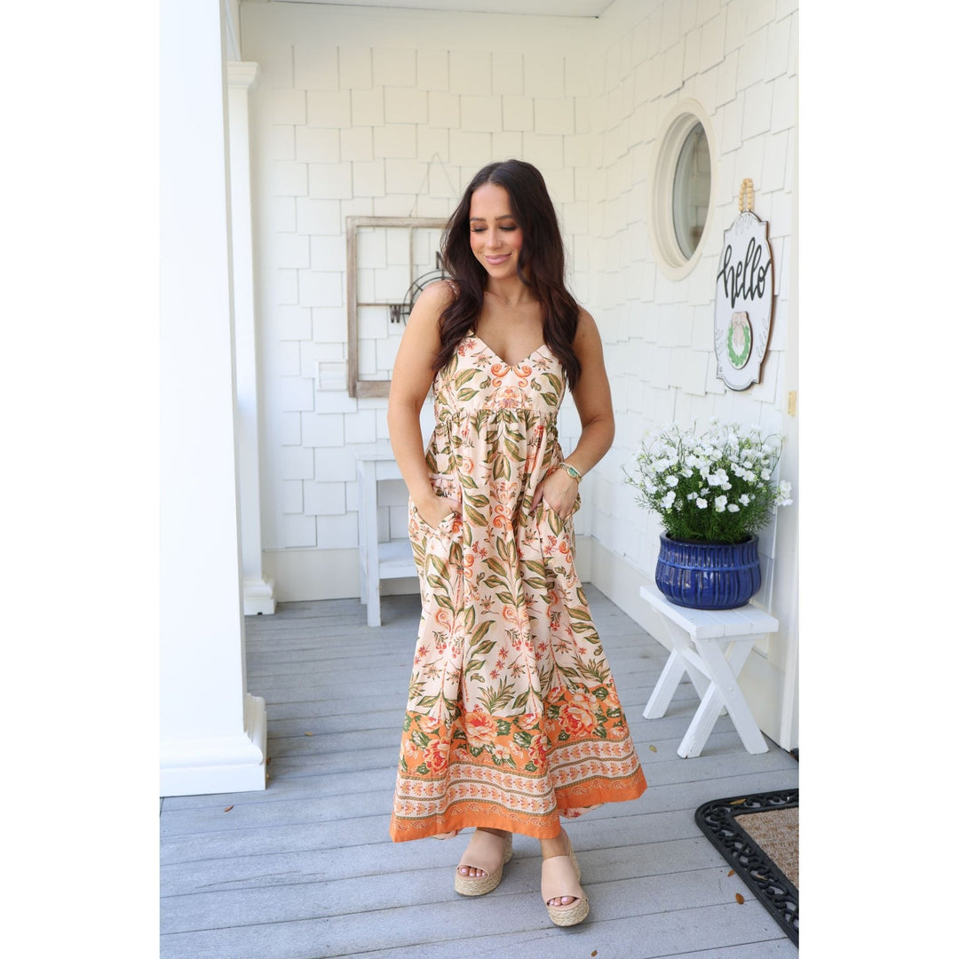 Woman in a floral dress standing on a porch 