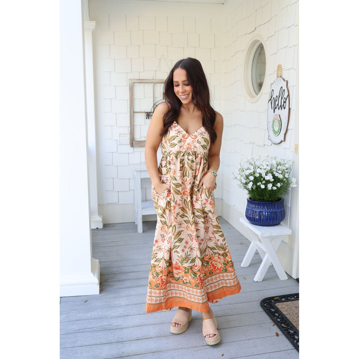 Woman in a floral dress standing on a porch 