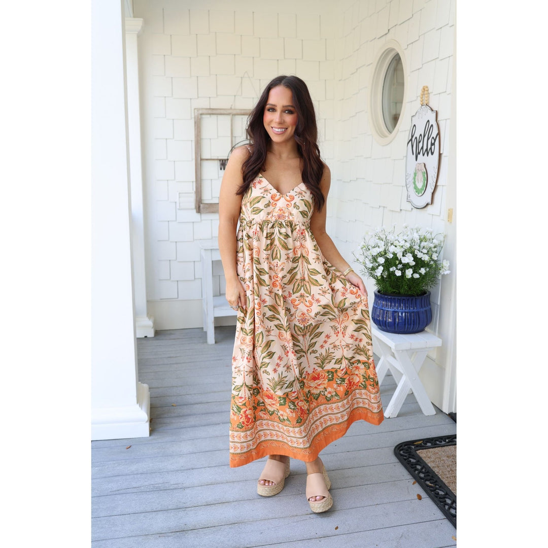 Woman in a floral dress standing on a porch 
