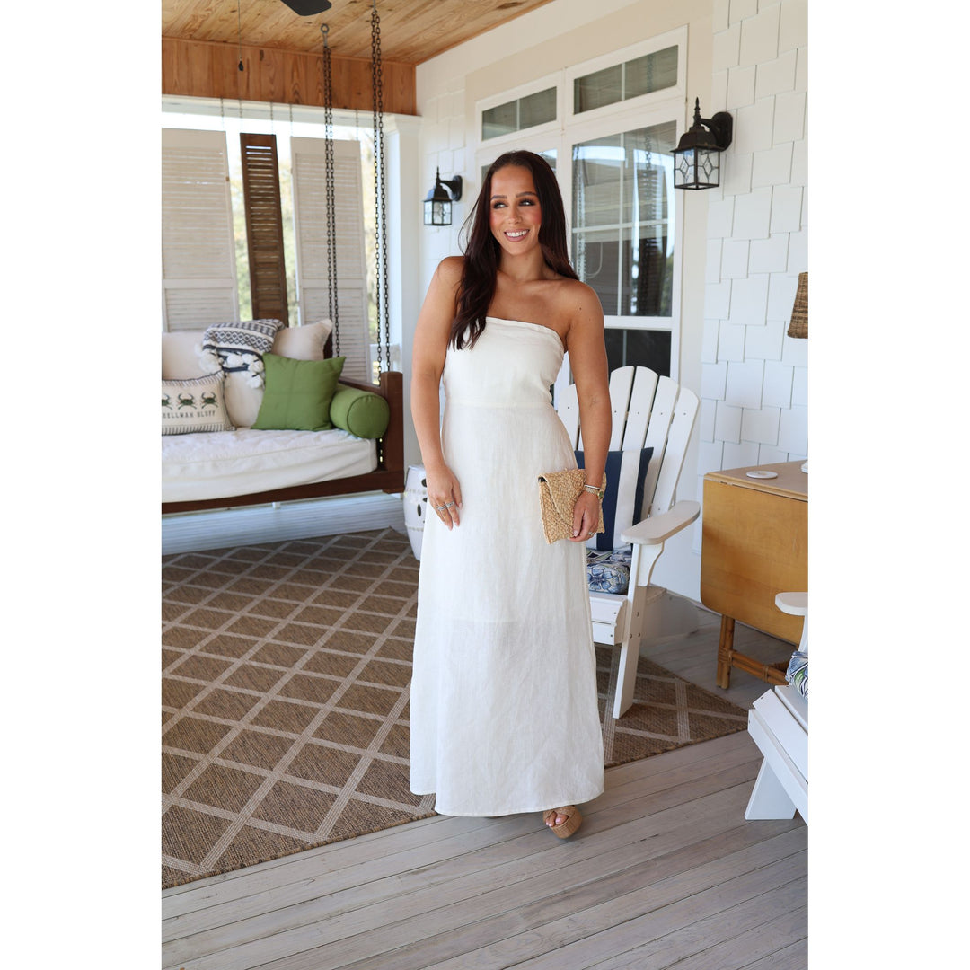 Woman in a white strapless dress standing on a wooden deck.