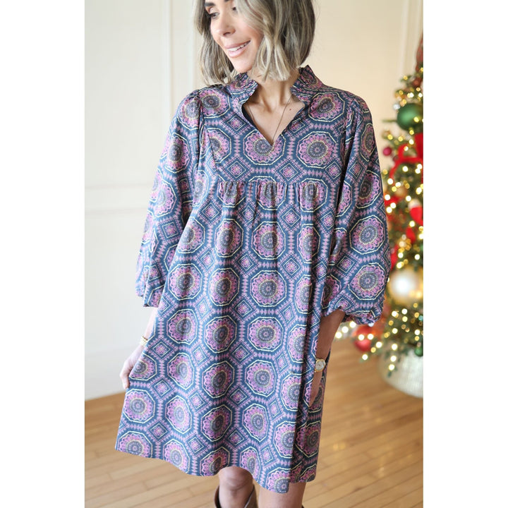 Woman wearing a patterned dress in front of a decorated Christmas tree.