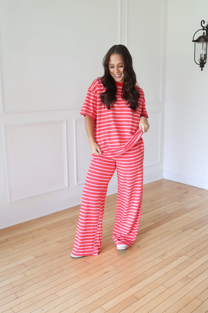A woman modeling a matching two-piece lounge set with red and white horizontal stripes, consisting of a short-sleeve top and wide-leg pants