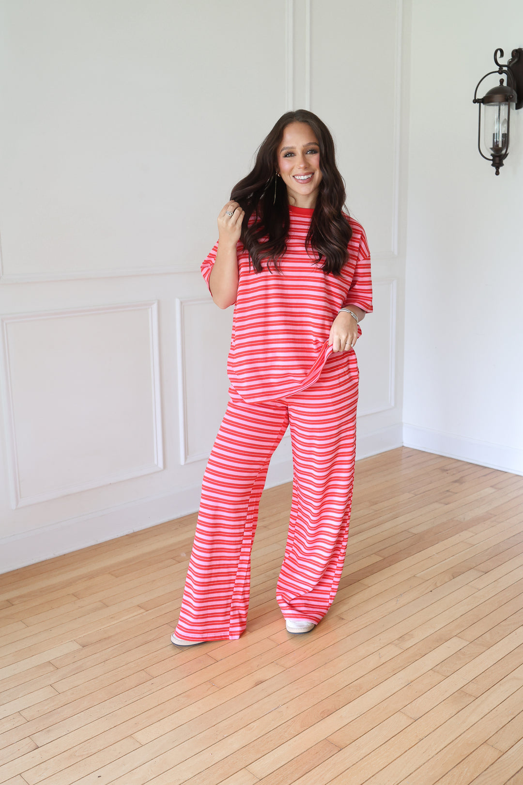 A woman modeling a matching two-piece lounge set with a red and white striped t-shirt and wide-leg pants