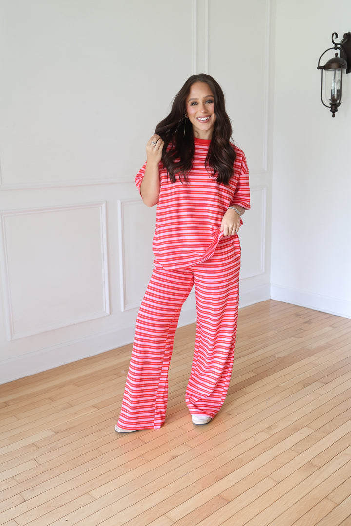 A woman modeling a matching two-piece lounge set with a red and white striped t-shirt and wide-leg pants