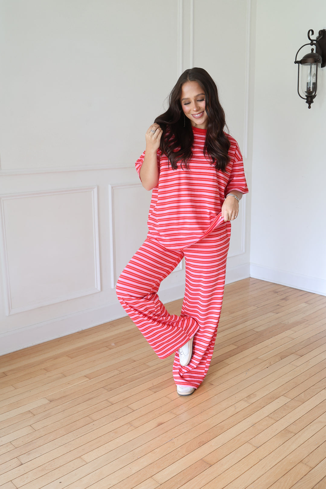 A woman modeling a matching two-piece loungewear set with red and white horizontal stripes, consisting of a short-sleeve top and wide-leg pants