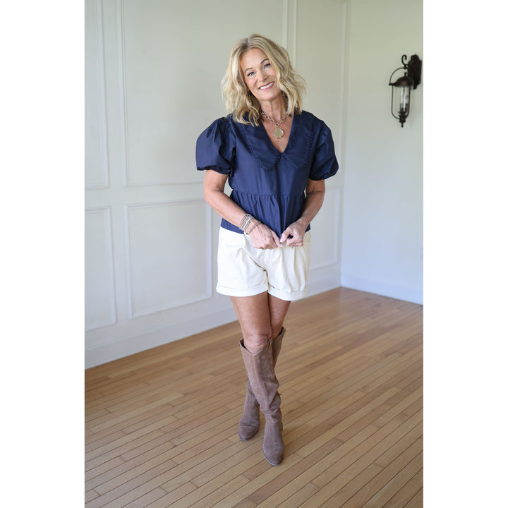 Woman wearing a blue top and white shorts with brown boots