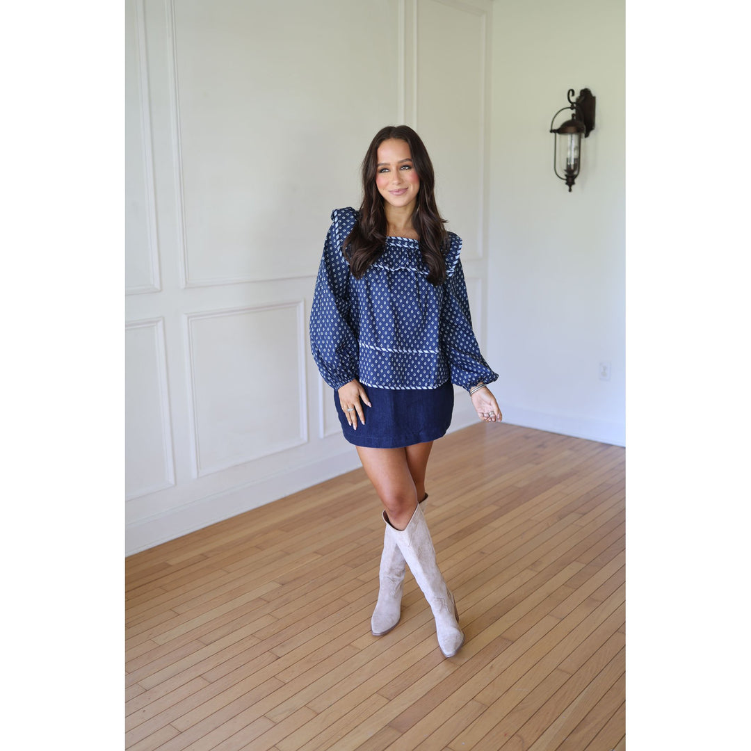 Woman wearing a blue  blouse and skirt with white knee-high boots