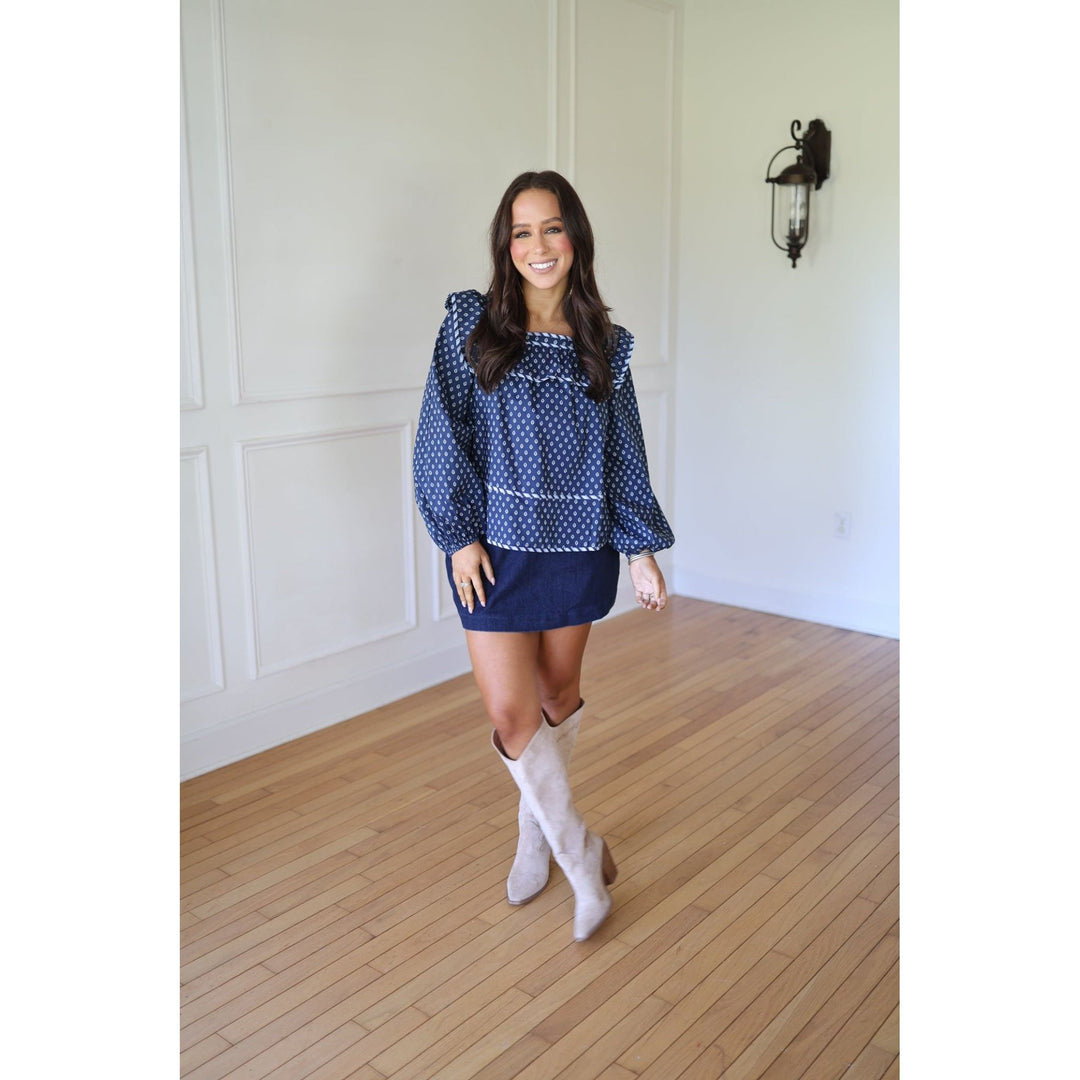 Woman wearing a blue blouse and skirt with white knee-high boots 