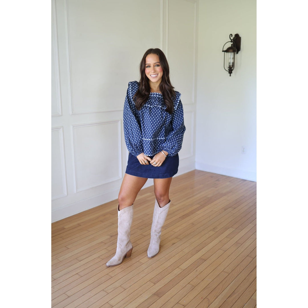 Woman in a blue  blouse and skirt with white knee-high boots 