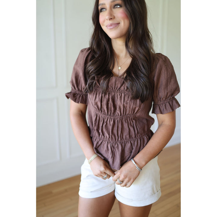 Woman wearing a brown top and white shorts 