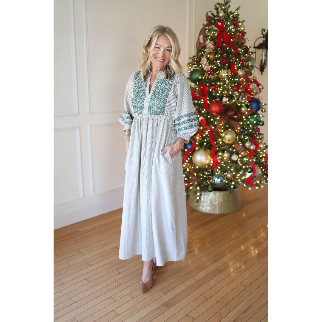 Woman in a long dress standing in front of a decorated Christmas tree.