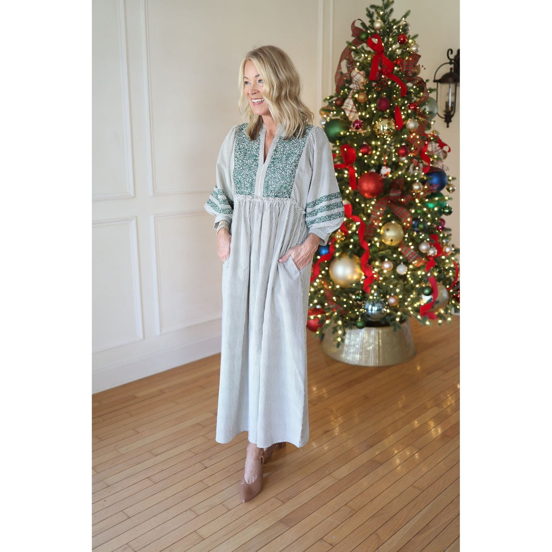Woman in a long dress standing in front of a decorated Christmas tree.