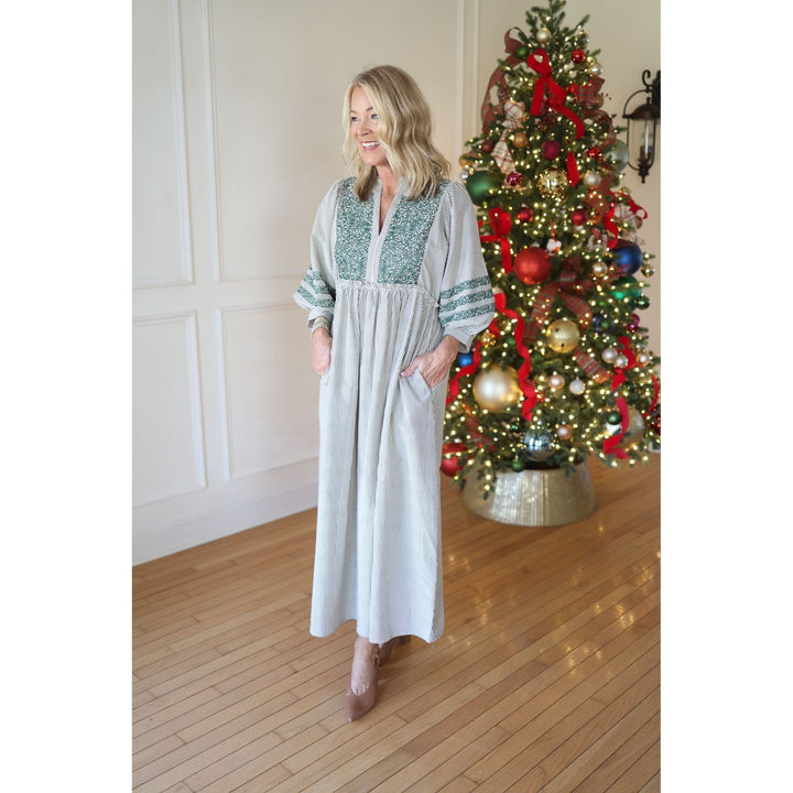 Woman in a long dress standing in front of a decorated Christmas tree.