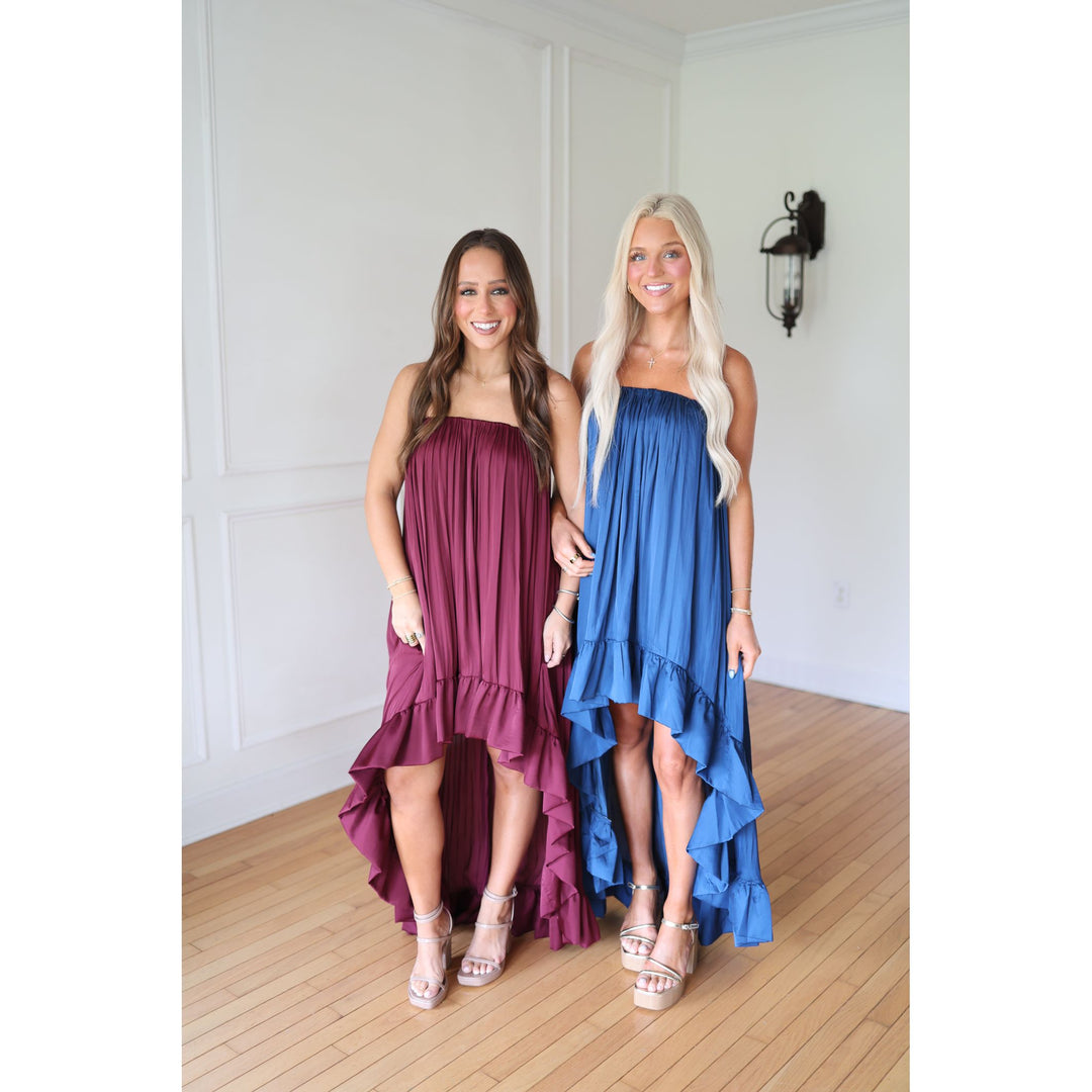 Two women wearing strapless dresses, one purple and one blue,