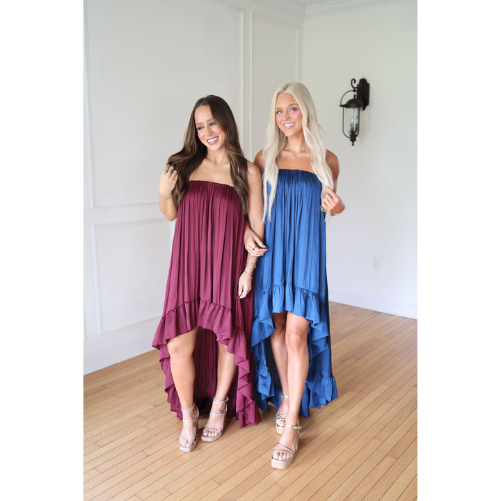 Two women wearing strapless dresses, one in maroon and the other in blue