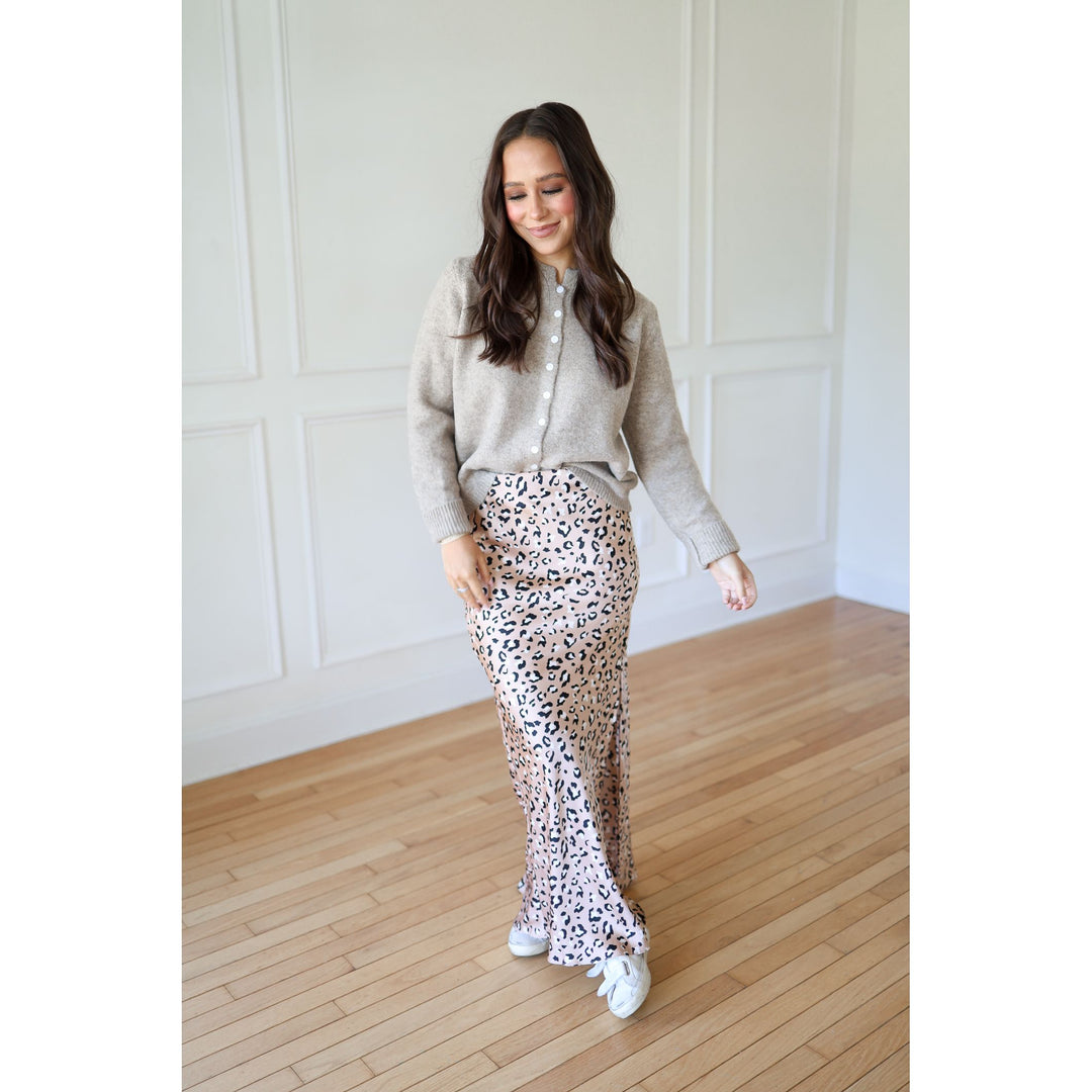 Woman wearing a light gray cardigan, patterned pants, and white sneakers 