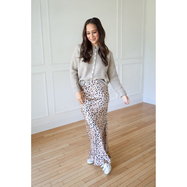 Woman wearing a light gray cardigan, patterned pants, and white sneakers 