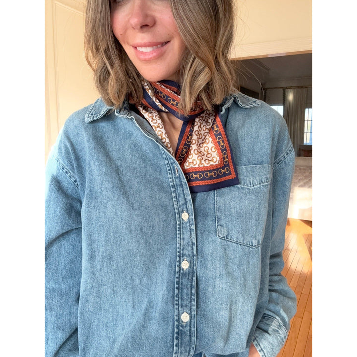 Person wearing a denim jacket with a patterned scarf