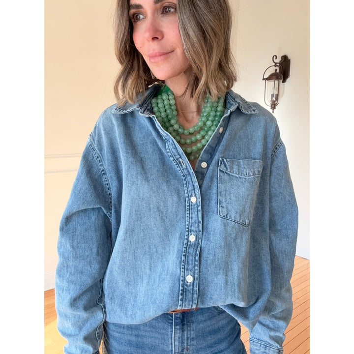 Woman wearing a blue denim shirt with a green necklace