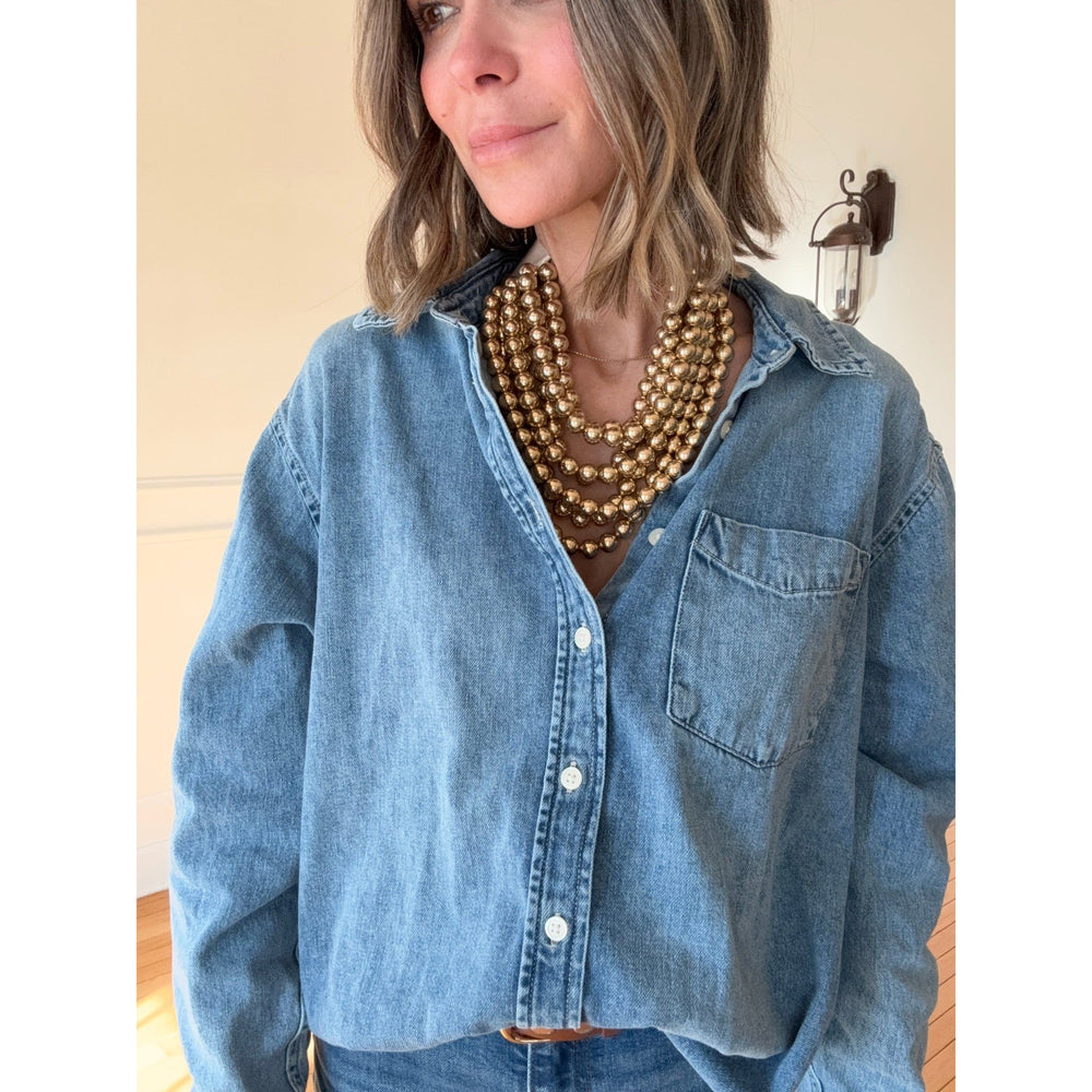 Person wearing a blue denim shirt and  gold necklace