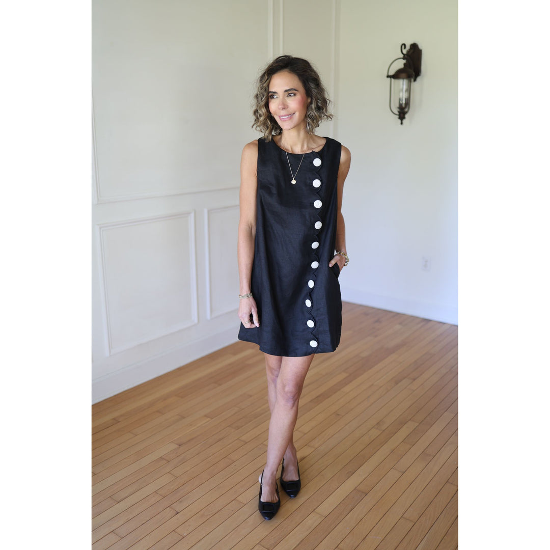 Woman wearing a black dress with white buttons 