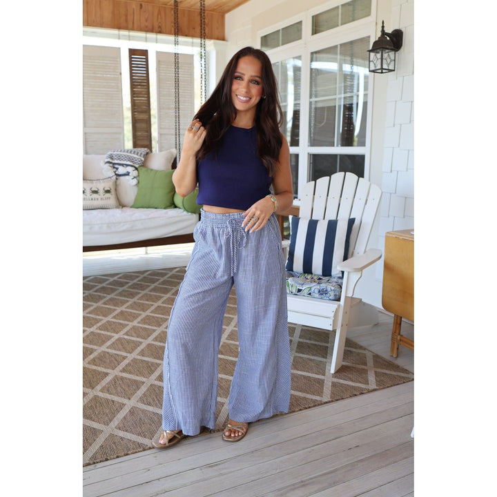 Woman in blue top and light blue plaid pants standing on a wooden deck.