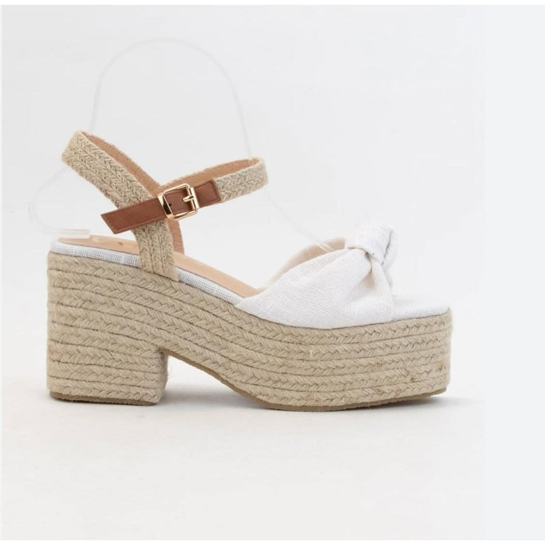 White sandal with brown woven sole and strap on a white background
