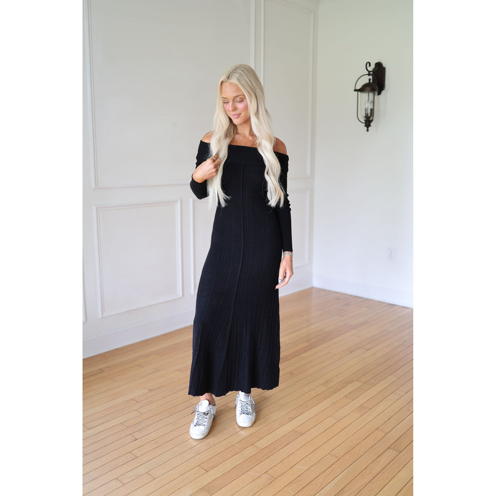 Woman wearing a black off-shoulder dress and white sneakers 