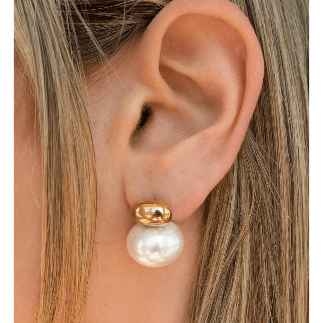 Pearl earring with gold cap worn by a person