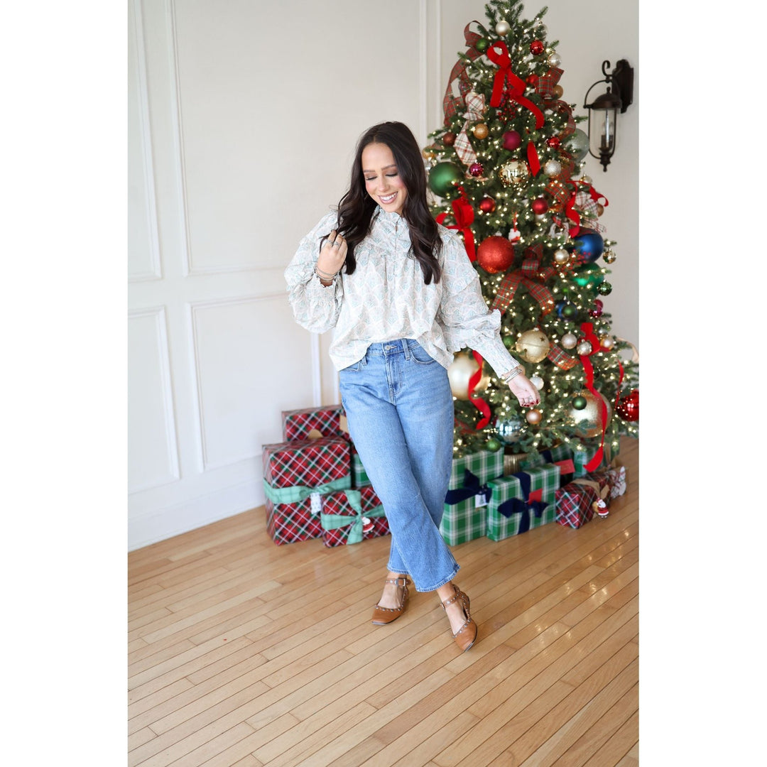 Woman posing in front of a decorated Christmas tree with presents underneath.