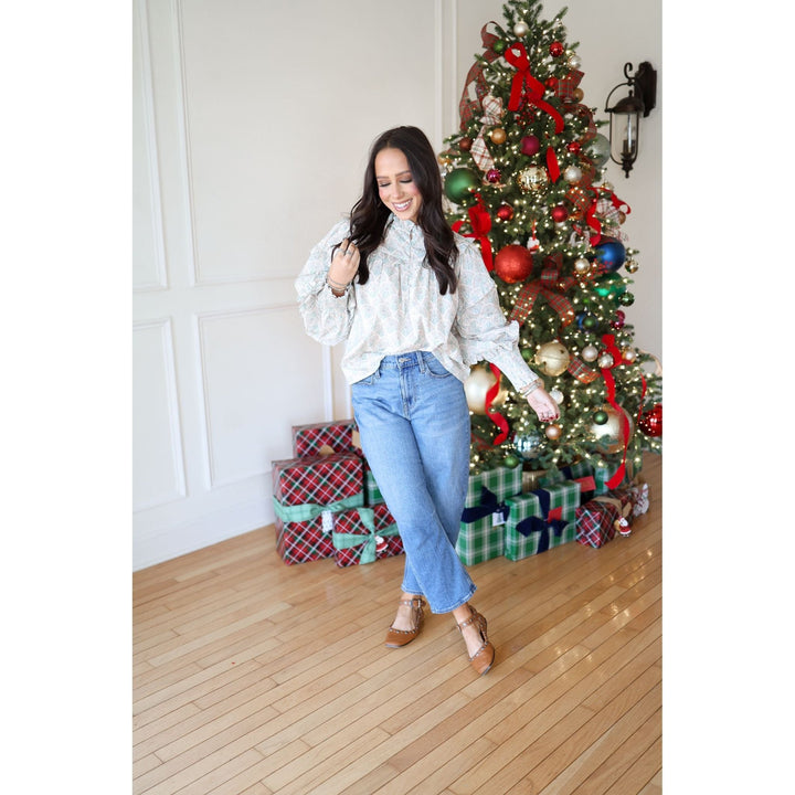 Woman posing in front of a decorated Christmas tree with presents underneath.