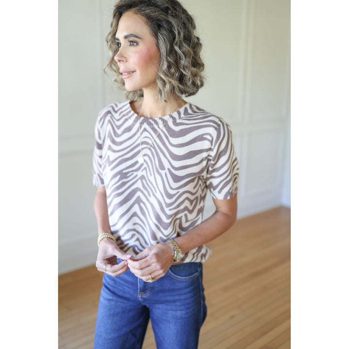 Woman wearing a zebra print top and blue jeans 